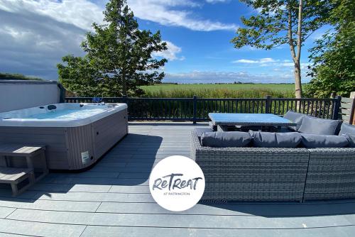 a patio with a hot tub and a couch and a table at ReTreat Breaks - 47 Park Lane in Patrington