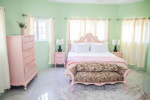 a bedroom with a large bed and a pink dresser at The Hamilton's Nature Villa in Clarks Town