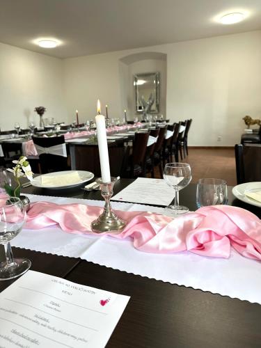 a table with a candle and a pink table cloth at Hotel Stará Pošta in Zdiby