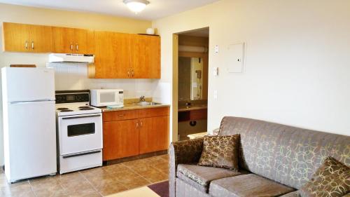 a kitchen with a couch and a white refrigerator at Alpine Motel in Kamloops