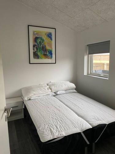 a bed in a bedroom with a picture on the wall at Fin ny moderniseret lejlighed i Skagen. in Skagen