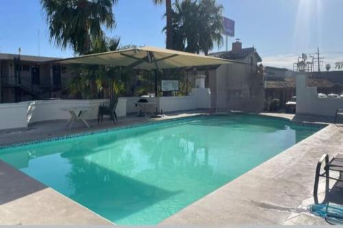 a large swimming pool with an umbrella and chairs at Hotel Siesta Real in Mexicali