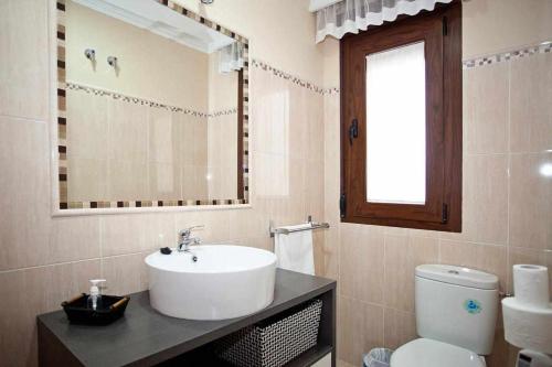 a bathroom with a sink and a toilet and a mirror at Apartamento Medina Las Eras in Güevéjar