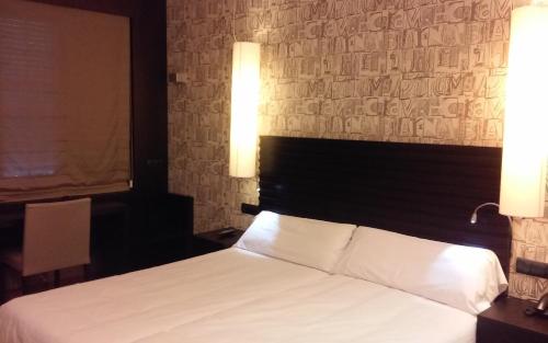 a bedroom with a white bed with two lights on it at Hotel Gastronómico Casa Rosalia in Brion