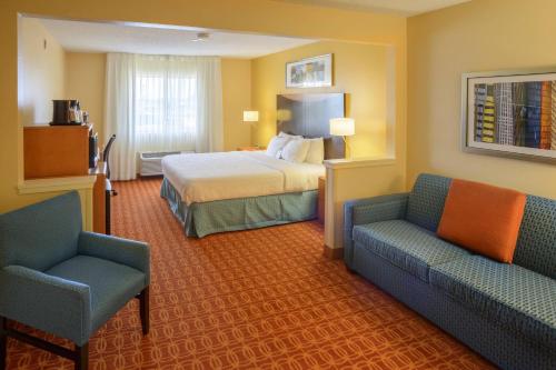 a hotel room with a bed and two chairs at Fairfield Inn Indianapolis South in Indianapolis