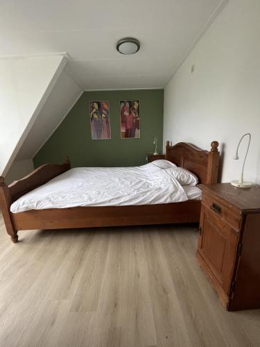 a bedroom with a large bed and a wooden dresser at Vakantiehuisjes Marsherne in Poppingawier