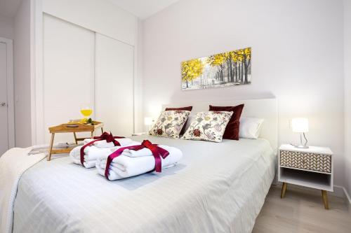 um quarto com uma cama branca com arcos vermelhos em -MalagaSunApts-SkyGarden Teatinos Pool Playground em Málaga