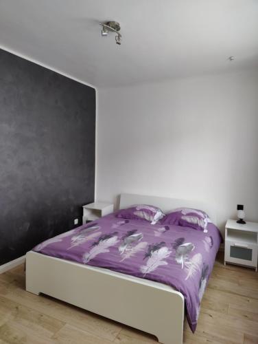 une chambre avec un lit avec une couette violette dans l'établissement Le Purple, appartement de standing en hypercentre, à Sarreguemines