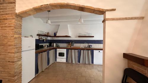 eine Küche mit weißen Geräten und einer Ziegelwand in der Unterkunft Casa Margherita in Alquézar