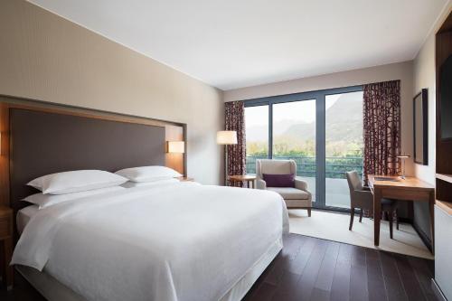 a hotel room with a bed and a large window at Sheraton Lake Como Hotel in Como