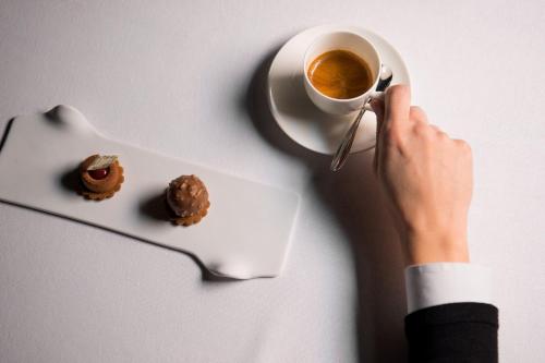 a person holding a cup of coffee and a plate of donuts at Sheraton Lake Como Hotel in Como