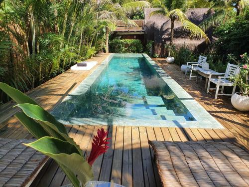 a swimming pool in a backyard with a wooden deck at Caiçara Bangalôs Barra Grande Maraú-BA in Barra Grande