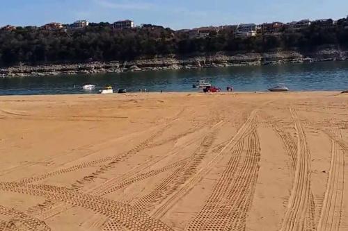 a beach with tire tracks in the sand and water at Lake Travis Oasis next to Pool, Marina, Boat ramp in Leander