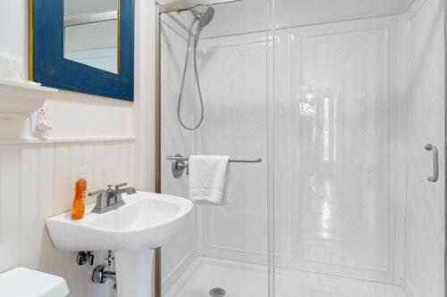 een witte badkamer met een douche en een wastafel bij Little Loon Farm in Waldoboro