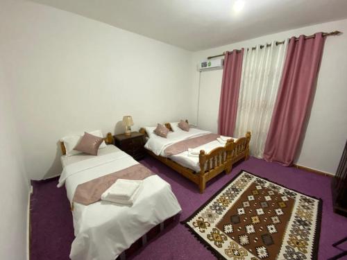 1 dormitorio con 2 camas y alfombra morada en taila hostel en Wadi Musa