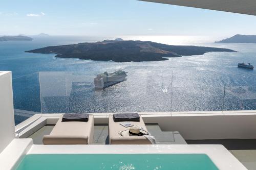 a balcony with two chairs and a view of the ocean at Thera Villas in Fira