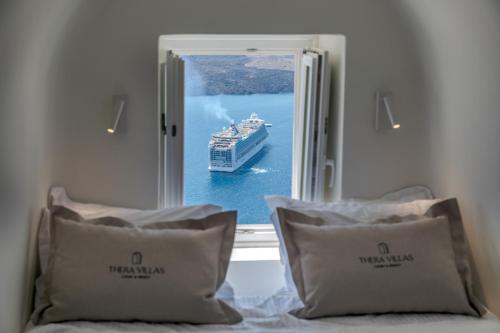 a cruise ship in the water through a window at Thera Villas in Fira