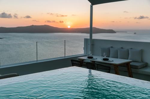 a view of the sunset from a balcony with a pool at Thera Villas in Fira