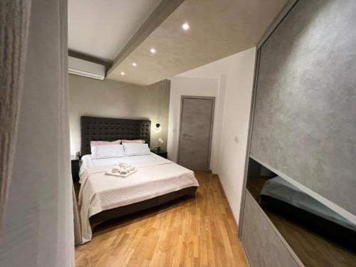 um quarto com uma cama com lençóis brancos e pisos em madeira em Maria's Elite Luxury Apartment Skopje em Skopje