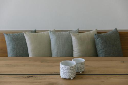 two cups sitting on a wooden table with pillows at Thera Villas in Fira