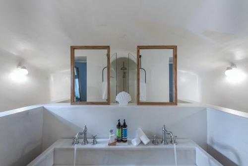 a bathroom with two sinks and two mirrors at Thera Villas in Fira