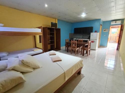 1 dormitorio con 2 camas y cocina con mesa en Sun Havens Apartments & Suites en Bocas del Toro