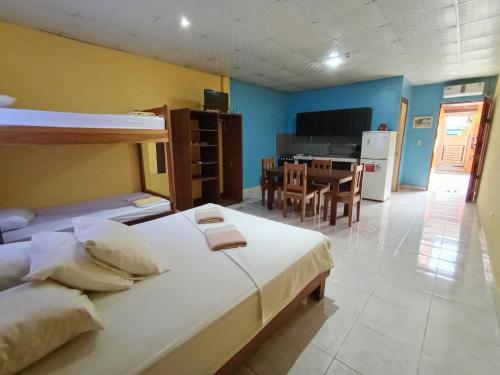 a bedroom with two beds and a kitchen with a table at Sun Havens Apartments & Suites in Bocas del Toro