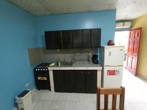a kitchen with black cabinets and a white refrigerator at Sun Havens Apartments & Suites in Bocas del Toro