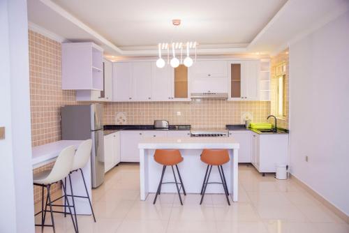 uma cozinha com armários brancos, uma mesa e bancos em Grazia Apartments em Kigali