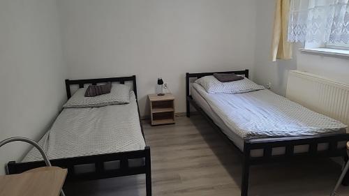 two beds in a room with a table and a window at Noclegi in Starogard Gdański