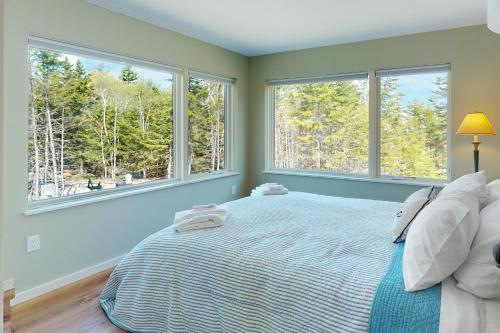 a bedroom with a bed and two windows at Tree House at Harts Neck in Saint George
