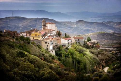 ein kleines Dorf auf einem Hügel mit Bergen im Hintergrund in der Unterkunft Casa Calma en Sierra de Vicort, Zaragoza in Inogés
