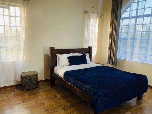 een slaapkamer met een bed met een blauwe deken en 2 ramen bij Lifestyle Villas, Nanyuki in Nanyuki