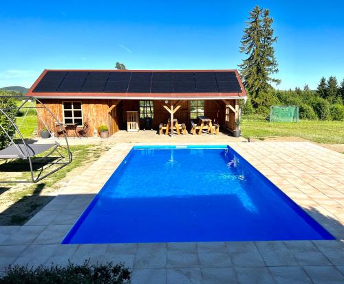 a large blue swimming pool in front of a house at Holiday home Hůrka in Hurka