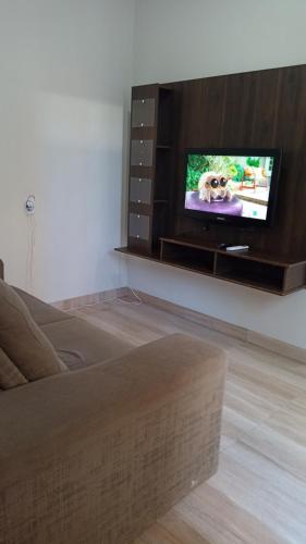 a living room with a tv with a dog on the screen at AP 2 quartos e cozinha de uso exclusivo in Sorriso