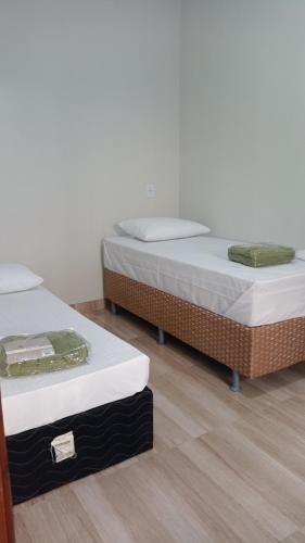 two beds sitting in a room with wooden floors at AP 2 quartos, 1 ar condicionado, com cozinha de uso exclusivo in Sorriso