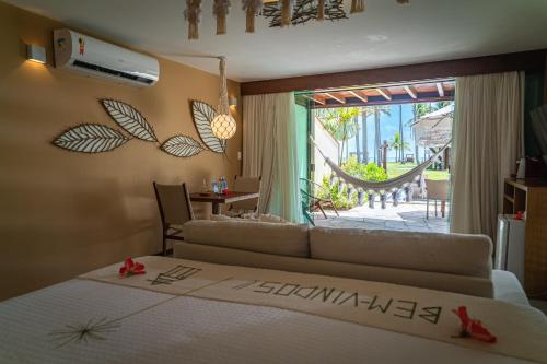 a bedroom with a bed and a view of a patio at Pontal dos Carneiros Beach Bungalows in Praia dos Carneiros