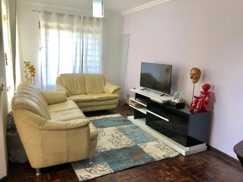 a living room with a couch and a television at Triplex Cor de Chicletes in Curitiba