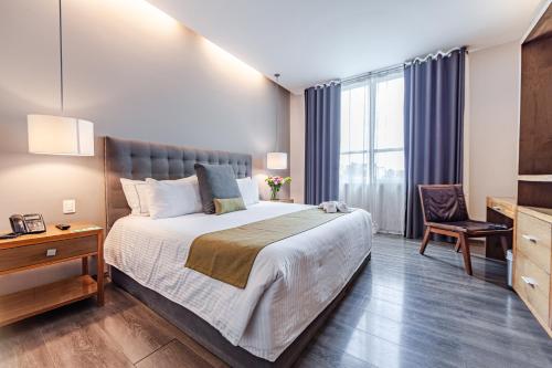 una habitación de hotel con una cama grande y una silla en Suites Del Ángel, en Ciudad de México