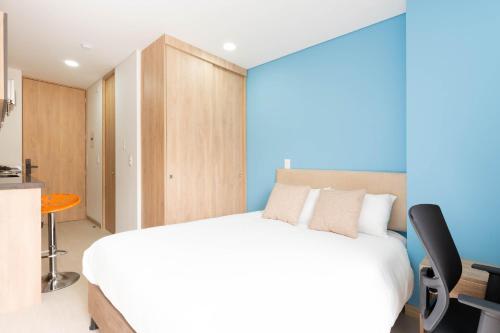 um quarto com uma cama branca e uma parede azul em Apartamentos Weeki en Chapinero em Bogotá