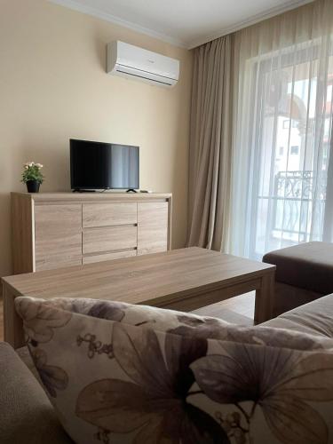 a living room with a table and a tv at South Beach Apartment at Valencia Gardens in Nesebar