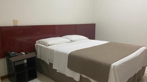 a bedroom with a large bed and a table at Manferrari Hotel in Contagem