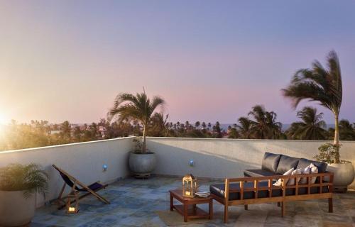 a patio with a couch and a table and palm trees at Aiolos Hotel & Discoveries in Prea