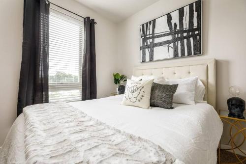 a bedroom with a white bed with pillows and a window at Fun & trendy condo close to downtown and the beach in Traverse City