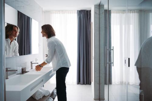 a woman standing in front of a sink in a bathroom at THE ONE CAORLE - Hotel & Apartments in Caorle