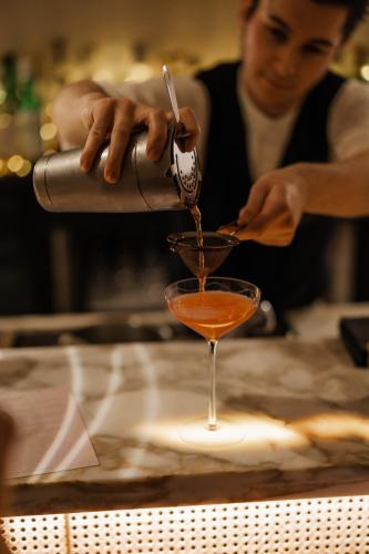 a woman is making a cocktail in a glass at The Roseate Villa Bath in Bath