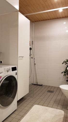 uma máquina de lavar roupa na casa de banho com um chuveiro em Hyvän unen huoneisto em Rovaniemi