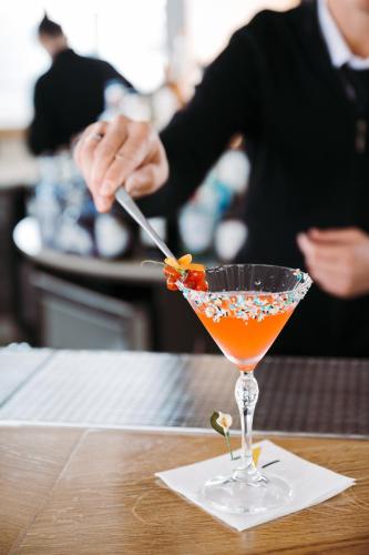 a person is stirring a drink in a martini glass at THE ONE CAORLE - Hotel & Apartments in Caorle