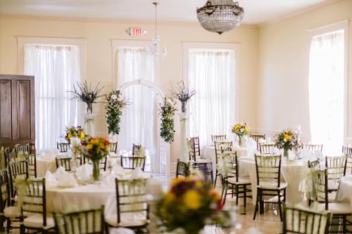 una stanza piena di tavoli e sedie con fiori di The Lasker Inn a Galveston