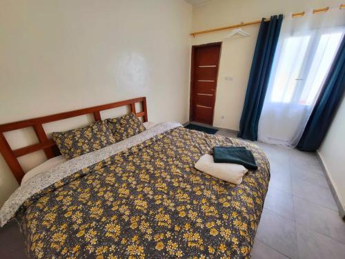 Iknews Appart Dakar في Kammba: غرفة نوم بسرير مع لحاف ومخدة